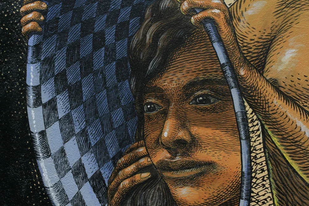 Close up mural detail of a face painted in fine cross hatching, hands lifting a checkered veil against a starry black background.