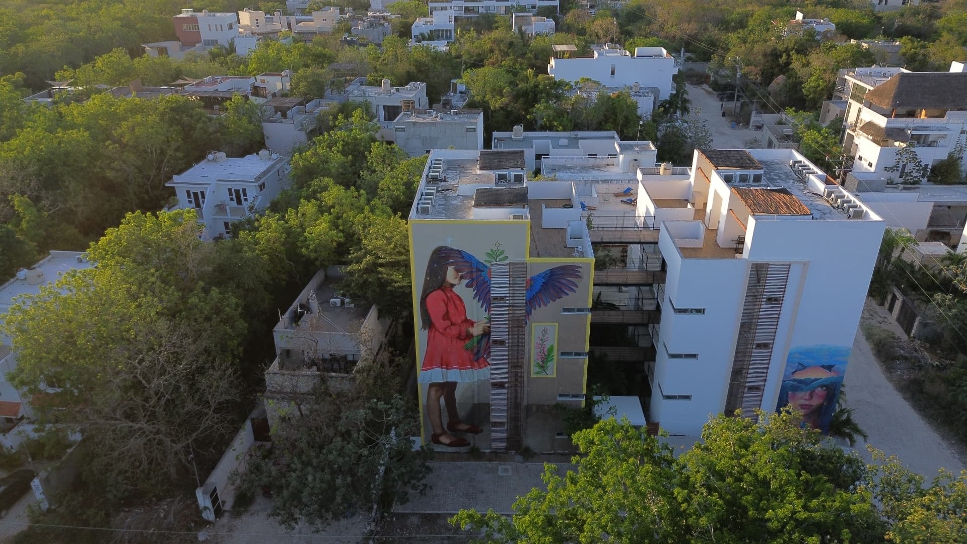 Aerial view of a mural of a girl with wings on a Tulum building