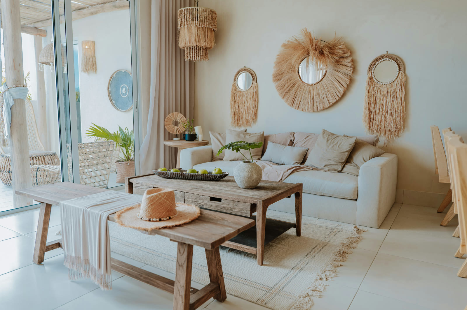 Bright beige living room with woven palm mirrors, neutral sofa, reclaimed wood coffee table and natural fibre accents.
