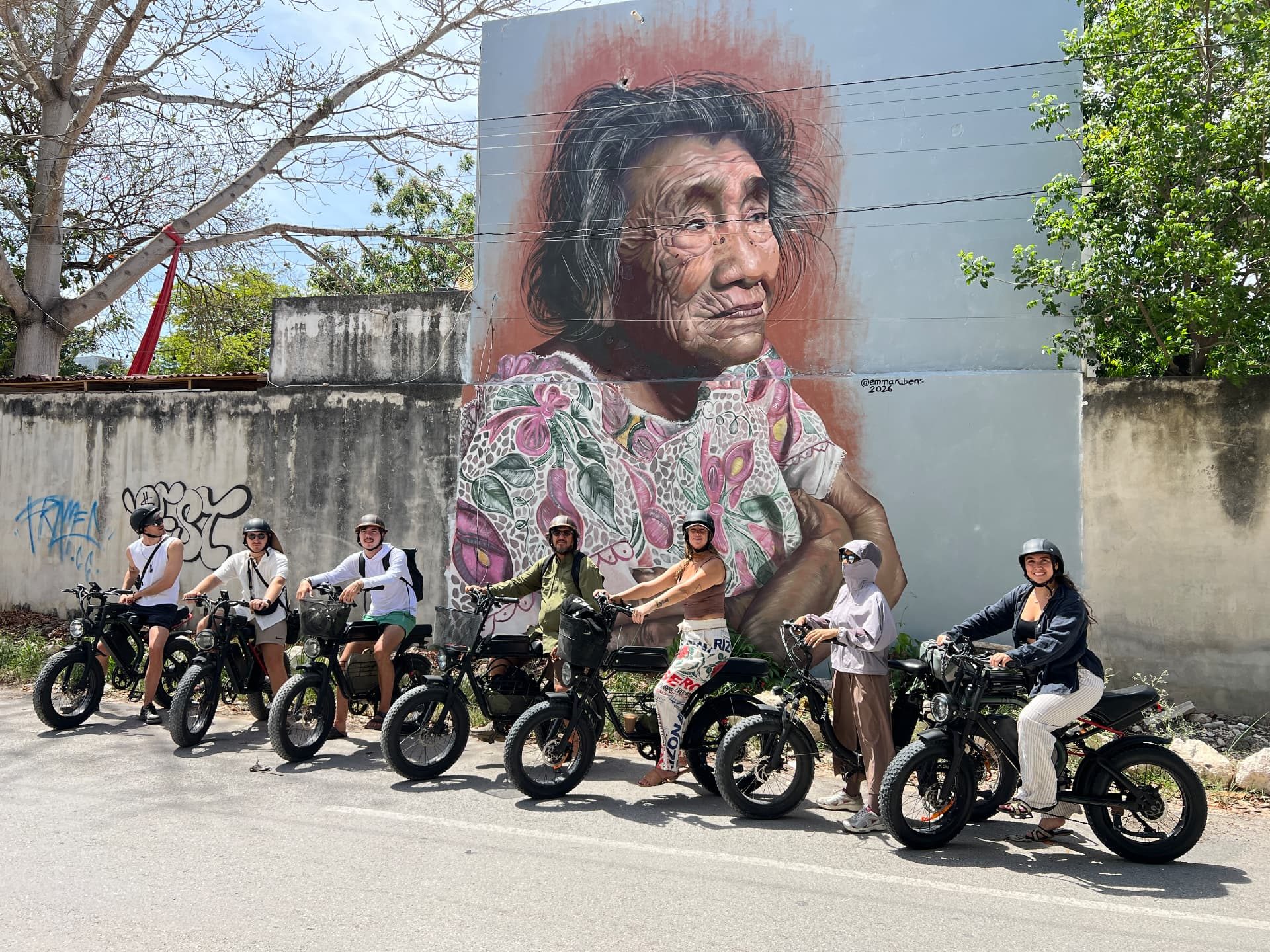 Small group on a guided e-bike art route in front of a Tulum mural
